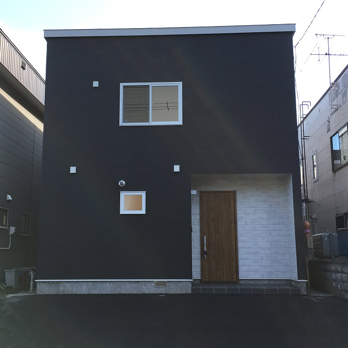 シックな灰色の外壁に木目の玄関ドアが映えるモダンな住宅外観